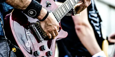Muzyk gra na gitarze, przygotowując się do wykonania coverów piosenek.