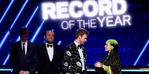 Billie Eilish odbiera nagrodę za nagranie roku. Na scenie towarzyszą jej Finneas O'Connell i inni.