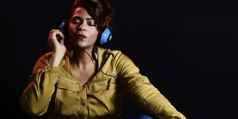 Kobieta w słuchawkach, z zamkniętymi oczami, słucha najlepszy wokalny album - pop.