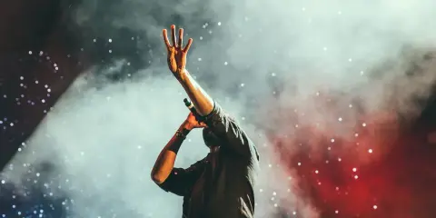 Artysta na scenie, w dymie i świetle, wykonuje fajne covery znanych piosenek.
