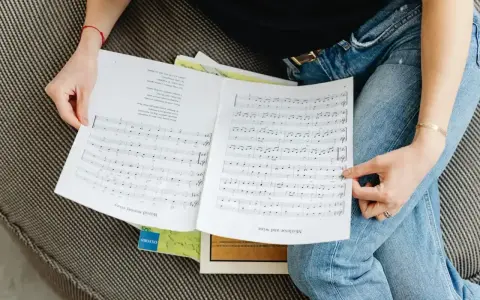 Osoba przegląda nuty, na których widnieje cząstka utworu muzycznego.
