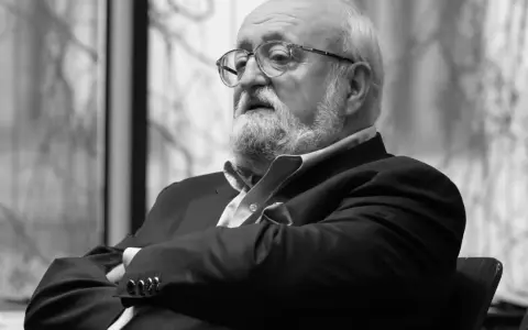 Krzysztof Penderecki w okularach, z brodą, w garniturze. Jego utwory to arcydzieła muzyki współczesnej.