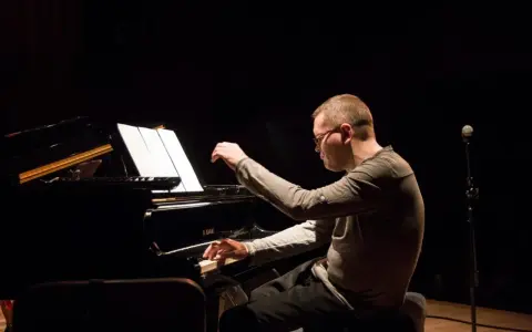 Znany polski kompozytor i pianista jazzowy, w skupieniu gra na fortepianie podczas koncertu.