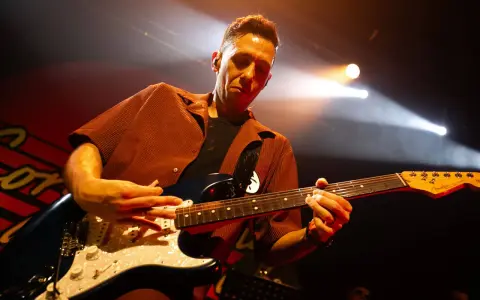 Cory Wong w akcie tworzenia muzyki na scenie, skupiony na grze na gitarze elektrycznej.