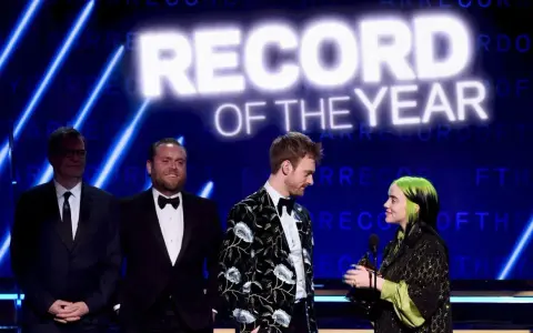 Billie Eilish odbiera nagrodę za nagranie roku. Na scenie towarzyszą jej Finneas O'Connell i inni.