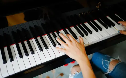 Dłoń grająca piosenkę na fortepianie Steinway.