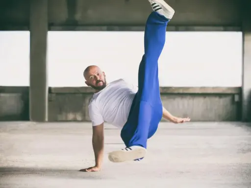 Mężczyzna w białej koszulce i niebieskich spodniach wykonuje akrobatyczny ruch. Czy to może być odpowiedź na pytanie: beatbox co to?