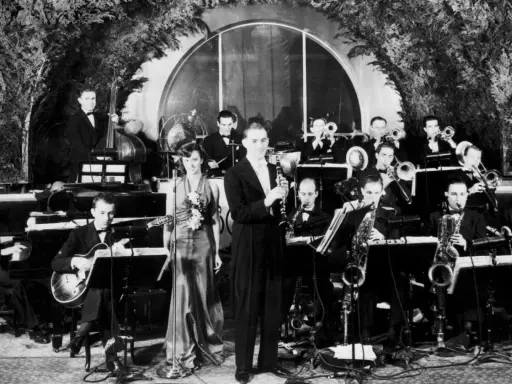 Orkiestra grająca muzykę lat 30. na scenie. Wokalistka w eleganckiej sukni, klarnetysta, gitarzysta i sekcja dęta.