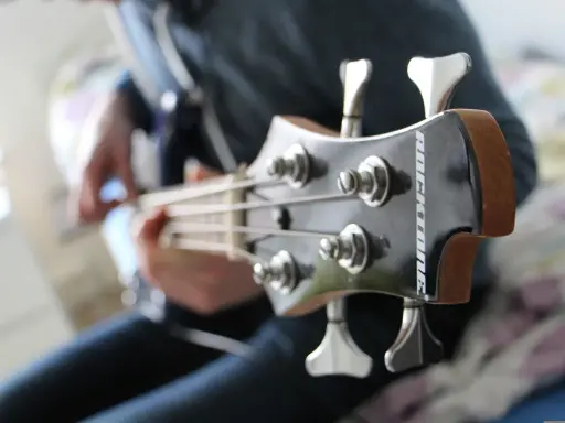Osoba gra na gitarze basowej, tworząc głębokie akordy basowe.