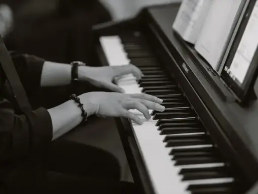 Dłonie grające na pianinie, tworząc improwizowany kierunek w muzyce jazzowej.