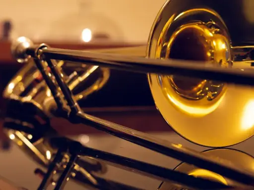 Błyszczące, złote puzony, różne rodzaje instrumentów dętych blaszanych, odbijające się w lustrzanej powierzchni.