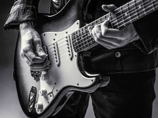 Ręce muzyka grające na gitarze do metalu. Czarno-białe ujęcie z bliska.
