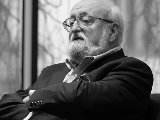 Krzysztof Penderecki w okularach, z brodą, w garniturze. Jego utwory to arcydzieła muzyki współczesnej.