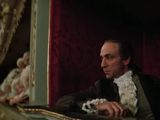 Scena z filmu o Mozarcie. Mężczyzna w stroju z epoki, w loży teatralnej, z widownią w tle.