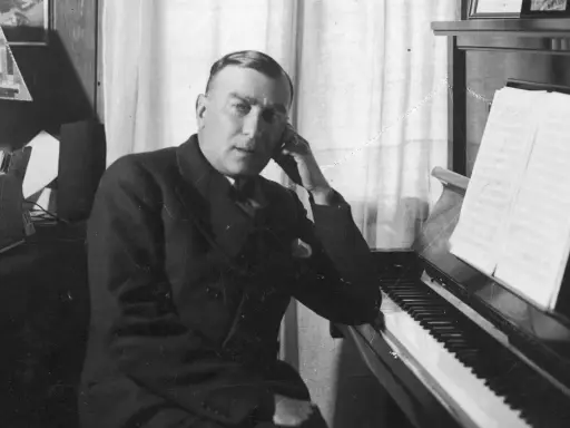 Karol Szymanowski, zamyślony przy fortepianie, z nutami na pulpicie.