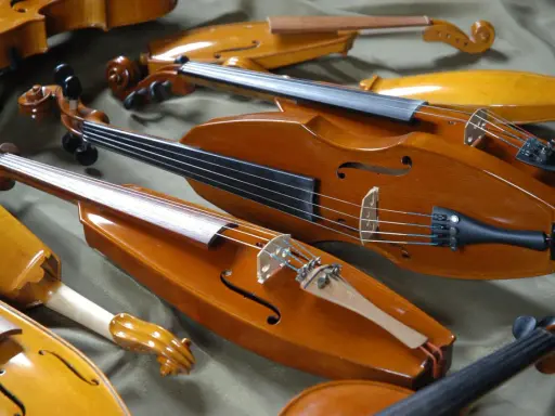 Kolekcja zabytkowych, drewnianych instrumentów smyczkowych. Te średniowieczne instrumenty, z ich ciepłym, lakierowanym wykończeniem, czekają na muzyków.