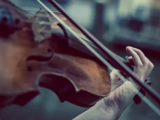 Dłoń gra na skrzypcach Stradivarius, wydobywając z nich magiczne dźwięki.