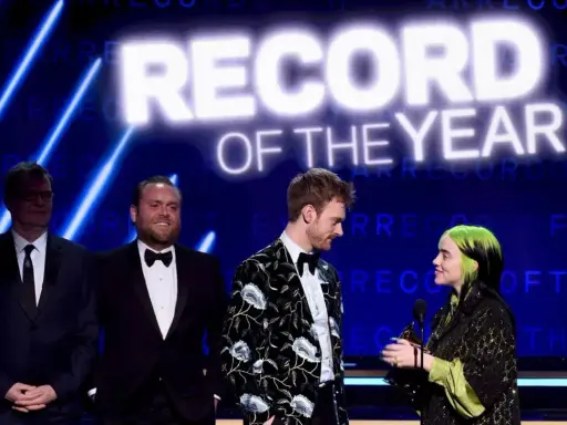 Billie Eilish odbiera nagrodę za nagranie roku. Na scenie towarzyszą jej Finneas O'Connell i inni.