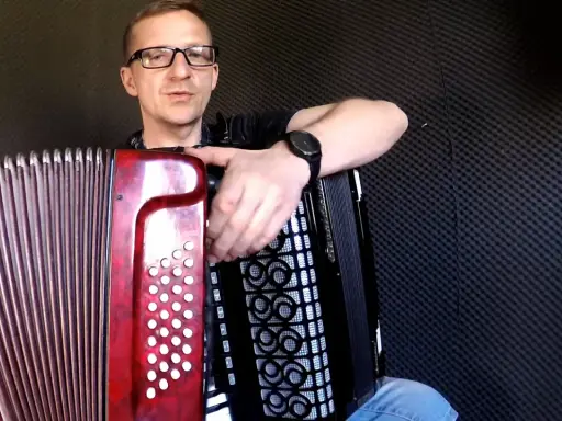 Mężczyzna w okularach uczy się grać na akordeonie. Lekcje gry na akordeonie dla dorosłych to świetny pomysł na rozwijanie pasji.