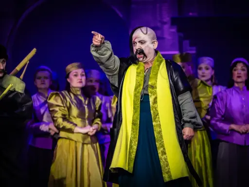 Aktorzy w barwnych strojach na scenie, przypominający postacie z operetki Moniuszki.