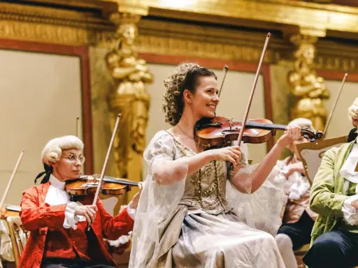 Koncert w stylu epoki Mozarta. W centrum uśmiechnięta kobieta grająca na skrzypcach, przypominająca żonę Mozarta.