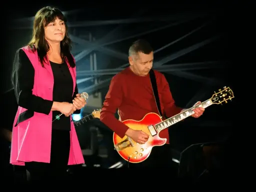 Kobieta z mikrofonem i mężczyzna grający na gitarze, polski blues wykonawcy na scenie.