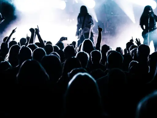 Tłum szaleje na koncercie, ręce w górze, światła sceny tworzą atmosferę legendy historii rocka.