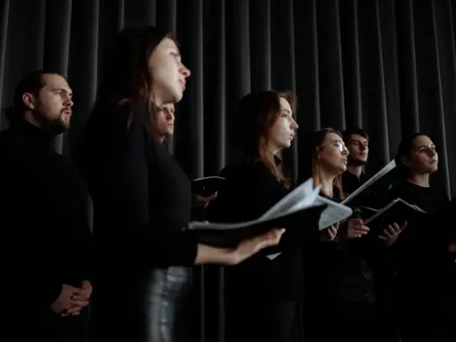 Chór w czarnych strojach, z nutami w rękach. Słychać głosy męskie i kobiece, tworzące harmonijną całość.