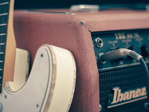 Biała gitara elektryczna podłączona do wzmacniacza Ibanez. Idealny zestaw, by zacząć naukę, jak grać na gitarze elektrycznej.