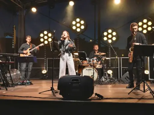 Zespół muzyczny na scenie: wokalistka, gitarzysta, klawiszowiec, saksofonista, basista i perkusista.