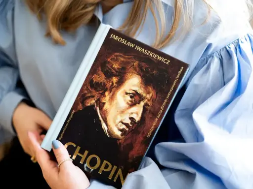 Kobieta trzyma książkę o Chopinie. Portret kompozytora na okładce. Piękna muzyka Chopina.