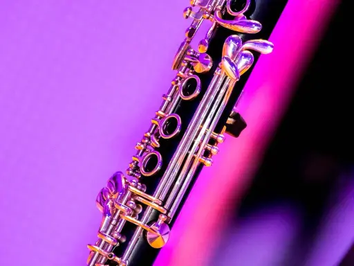 Zbliżenie na klarnet, piękny instrument dęty drewniany, z błyszczącymi klapami na tle fioletowo-różowego światła.