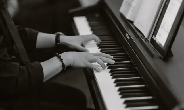 Dłonie grające na pianinie, tworząc improwizowany kierunek w muzyce jazzowej.