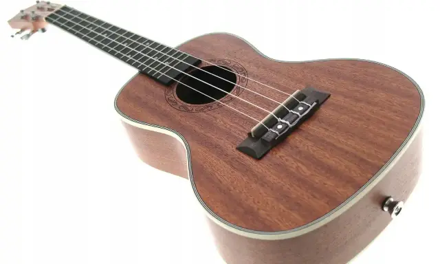 Brązowe ukulele z białym bindingiem, idealne do nauki gry na ukulele.