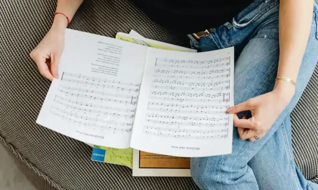 Osoba przegląda nuty, na których widnieje cząstka utworu muzycznego.