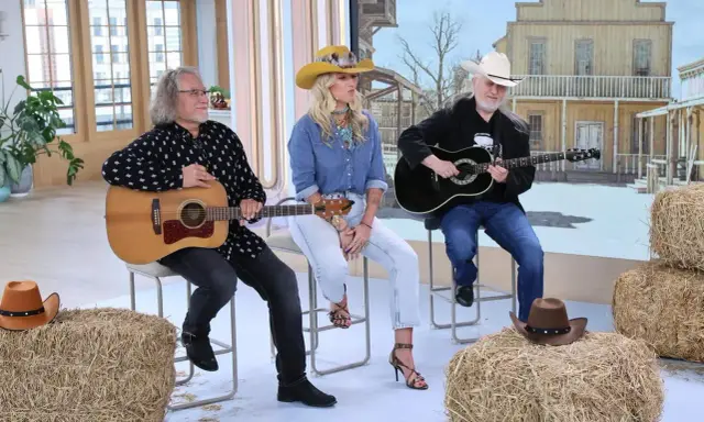 Trzech muzyków gra na gitarach, tworząc muzykę country. W tle stylizowana scenografia z Dzikiego Zachodu.