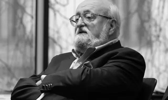 Krzysztof Penderecki w okularach, z brodą, w garniturze. Jego utwory to arcydzieła muzyki współczesnej.