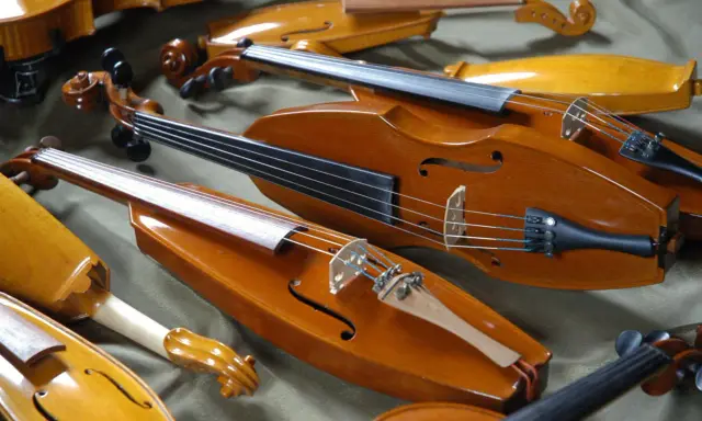 Kolekcja zabytkowych, drewnianych instrumentów smyczkowych. Te średniowieczne instrumenty, z ich ciepłym, lakierowanym wykończeniem, czekają na muzyków.