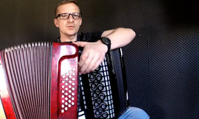 Mężczyzna w okularach uczy się grać na akordeonie. Lekcje gry na akordeonie dla dorosłych to świetny pomysł na rozwijanie pasji.