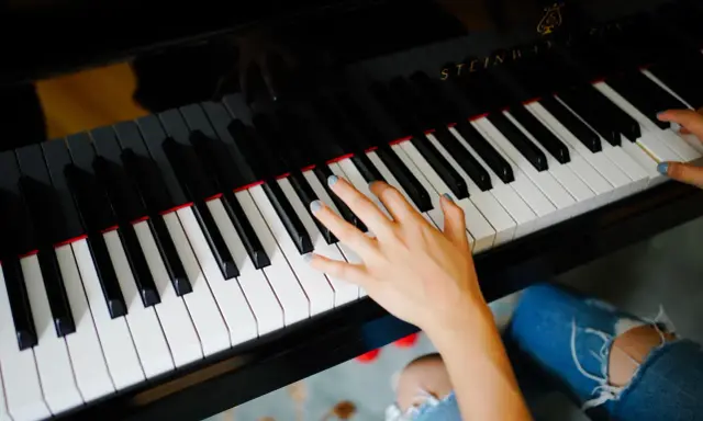 Dłoń grająca piosenkę na fortepianie Steinway.