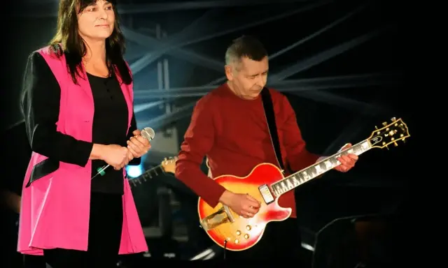 Kobieta z mikrofonem i mężczyzna grający na gitarze, polski blues wykonawcy na scenie.