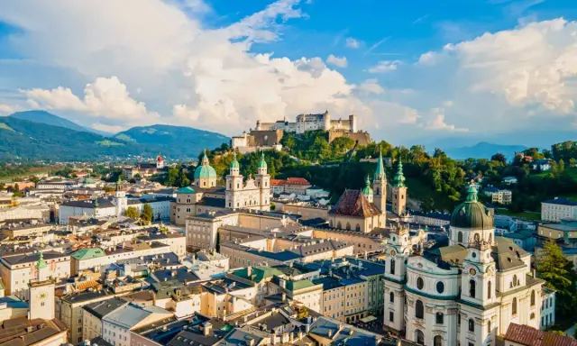 Widok na miasto z górami w tle, w tym Hohensalzburg. To ojczyzna Mozarta, Salzburga, z pięknymi kościołami i zabytkową architekturą.