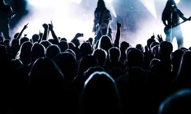Tłum szaleje na koncercie, ręce w górze, światła sceny tworzą atmosferę legendy historii rocka.