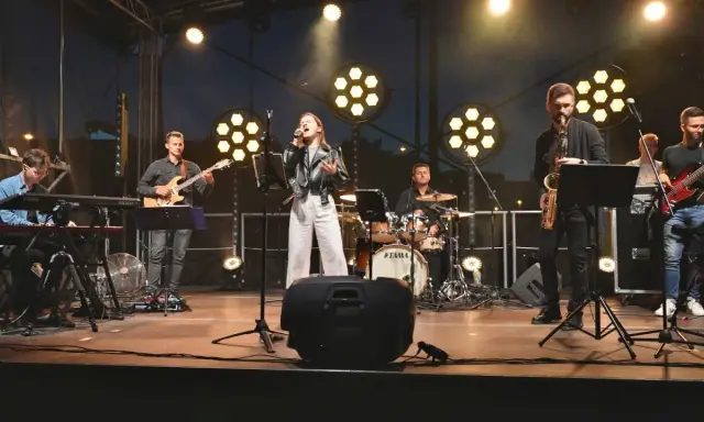 Zespół muzyczny na scenie: wokalistka, gitarzysta, klawiszowiec, saksofonista, basista i perkusista.