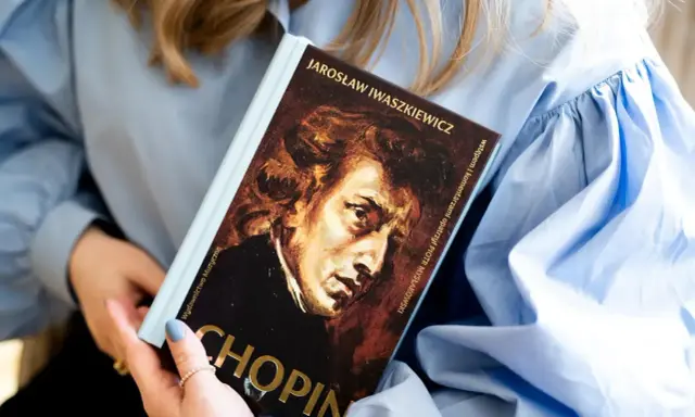 Kobieta trzyma książkę o Chopinie. Portret kompozytora na okładce. Piękna muzyka Chopina.
