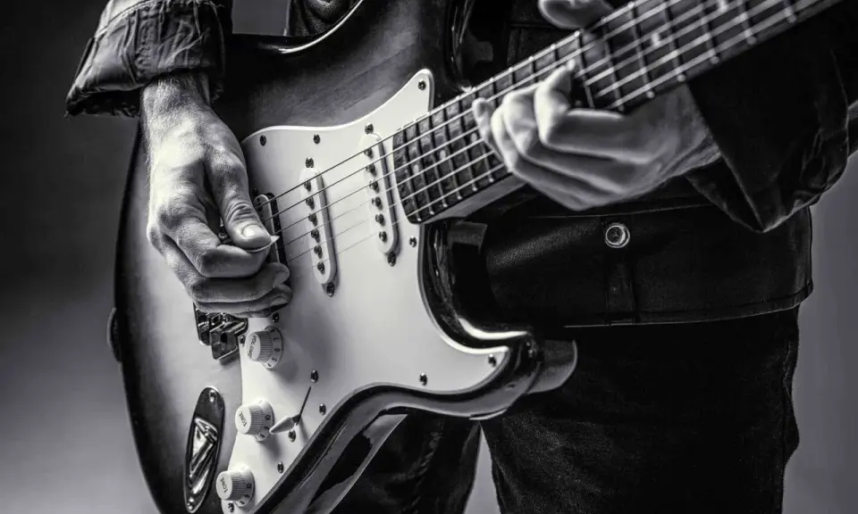 Ręce muzyka grające na gitarze do metalu. Czarno-białe ujęcie z bliska.