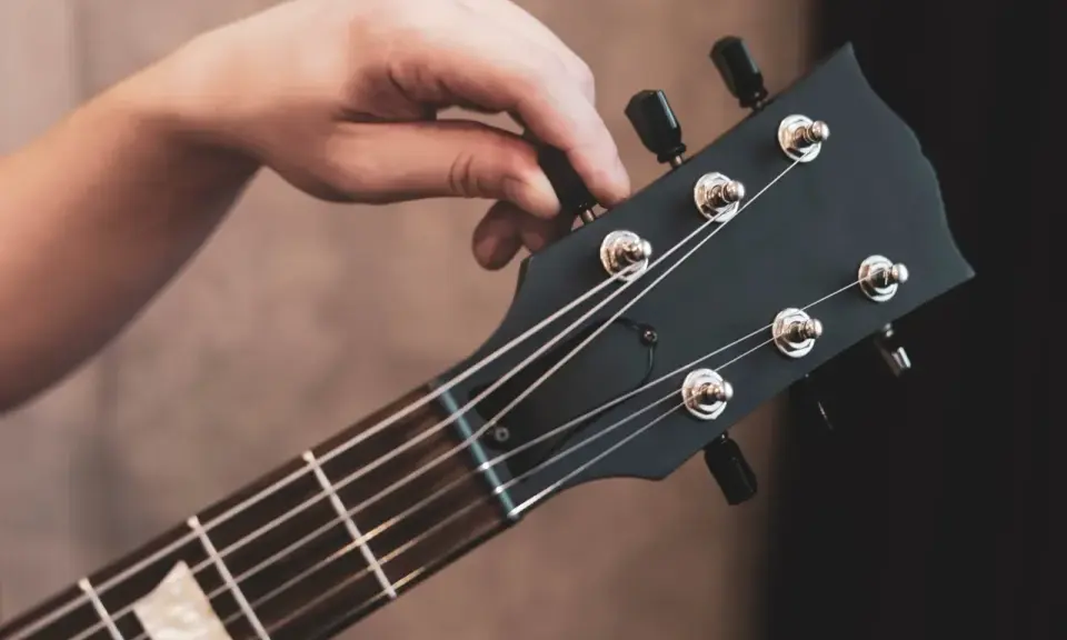 Dłoń kręci kluczem, by nastroić gitarę klasyczną. Idealne brzmienie czeka!