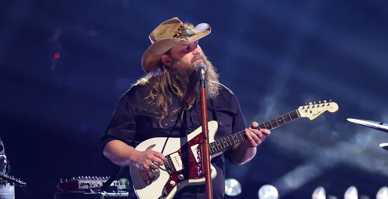 Wykonawca muzyki country w kapeluszu z piórami gra na gitarze.