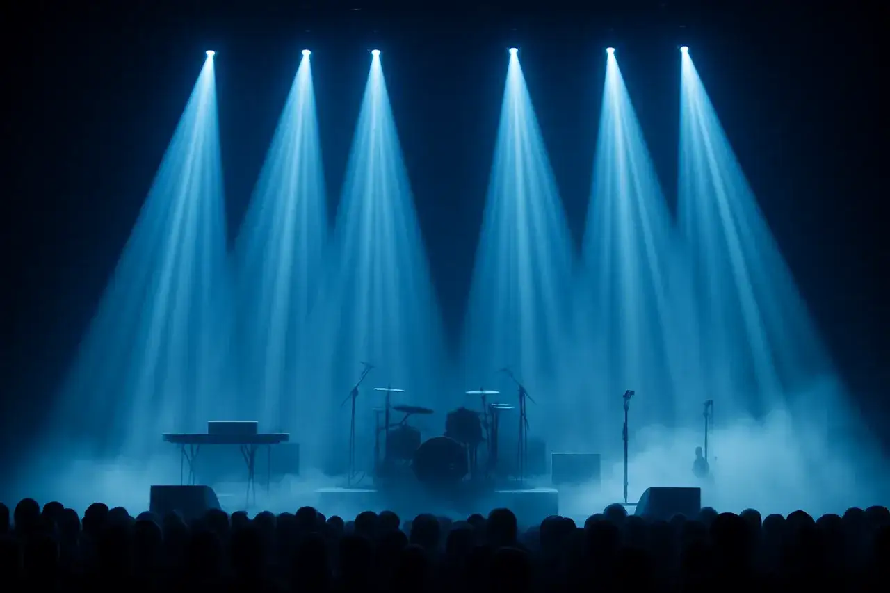 Scena koncertowa w niebieskich światłach, z instrumentami i gęstym dymem scenicznym.