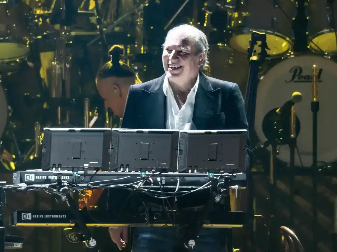 Uśmiechnięty Billy Joel, kto to kompozytor, gra na syntezatorze podczas koncertu.
